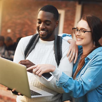 two students looking at a laptop outdoors