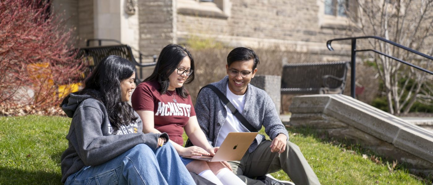 Students sitting on the grass at McMaster campus